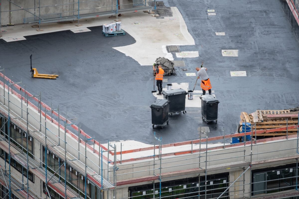 Roofer painting flat roof of a commercial building.